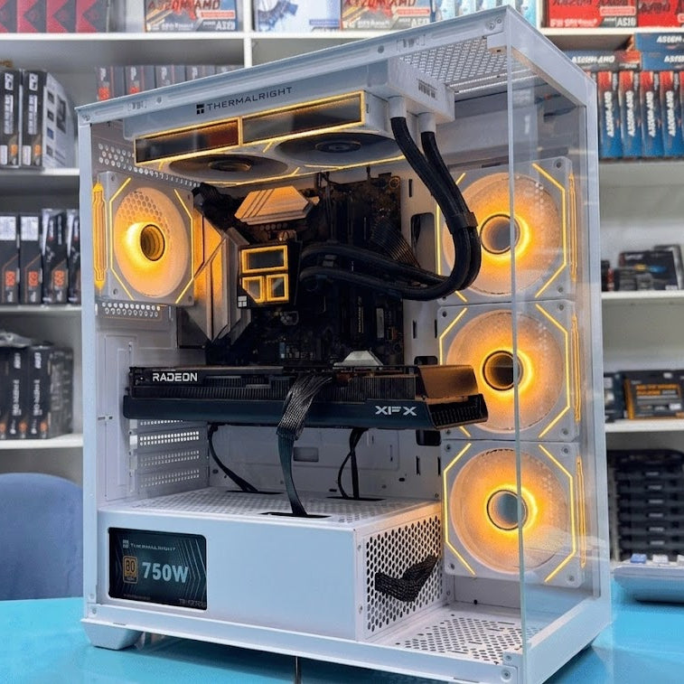 Open computer case with visible components on a blue surface, with shelves of computer parts in the background.